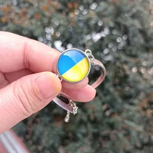 Dettaglio di un bracciale argento con un ciondolo rotondo con i colori della bandiera ucraina
