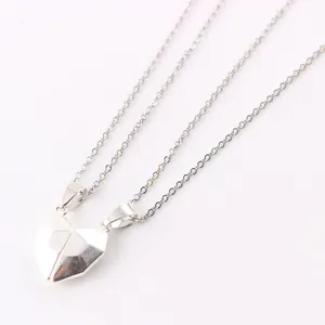 Magnetic heart couple necklaces set with silver geometric pendants on white background