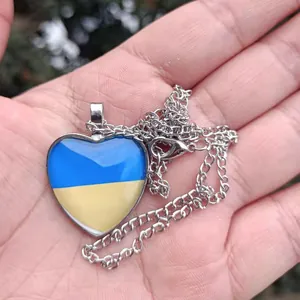 Detailaufnahme eines herzförmigen Ukraine-Flaggen-Halskettenanhängers an einer Silberkette