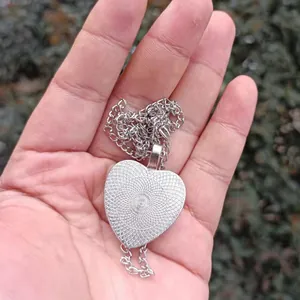 Detaillierte Rückansicht einer herzförmigen silbernen Halskette in der Hand gehalten