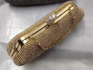 Detalle de un bolso de fiesta dorado con pedrería de cristal y correa de cadena.