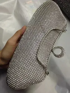 Detalle de bolso de mano plateado de lujo con pedrería brillante y anillo de dedo