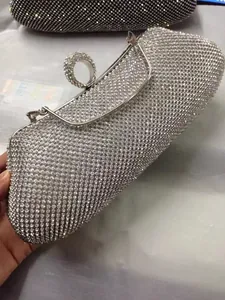 Vista detallada de un bolso de fiesta de pedrería plateada con asa de anillo de cristal.