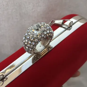 Close-up of elegant red velvet evening clutch with sparkling rhinestone ring clasp.