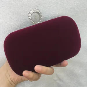 Close-up detail of a luxurious burgundy velvet evening clutch bag with rhinestone ring clasp