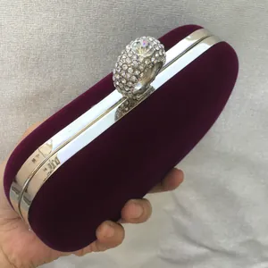 Detailed close-up of a purple velvet evening clutch featuring a sparkling rhinestone ring clasp