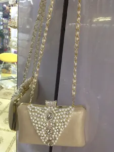 Detail view of a gold evening clutch bag with elegant pearl and rhinestone accents