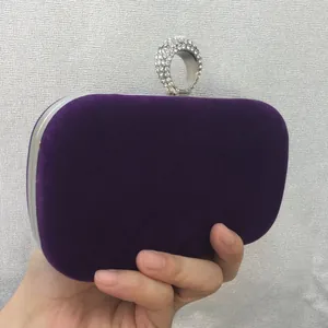 Detail of elegant purple velvet clutch bag featuring a sparkling rhinestone ring handle