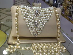 Detailed view of champagne evening clutch with pearl and rhinestone embellishments.