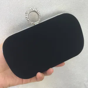 Close-up of black velvet evening clutch bag featuring a sparkling rhinestone ring clasp.