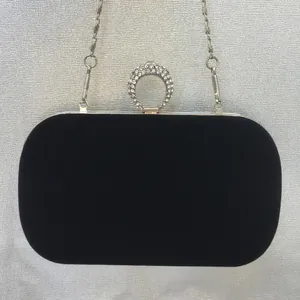 Detailed view of black velvet evening clutch with rhinestone ring clasp and silver chain