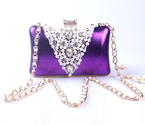 Detail view of purple evening clutch with pearls and crystal decorations on a gold chain.