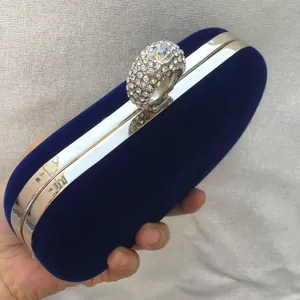 Close-up of blue velvet evening clutch bag with sparkling rhinestone ring clasp.