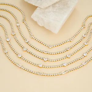 Primer plano detallado de varios collares tenis dorados brillantes sobre piedra blanca