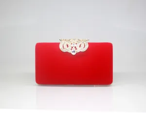 Detail of elegant red velvet evening clutch with crown-shaped rhinestone clasp
