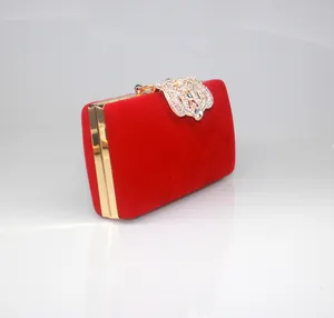 Close-up of red velvet evening clutch featuring a rhinestone-encrusted crown clasp