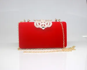 Close-up of elegant red velvet evening clutch with crown rhinestone clasp and gold chain