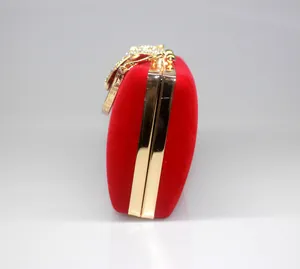 Side view of luxury red velvet clutch with gold frame and crystal crown clasp.