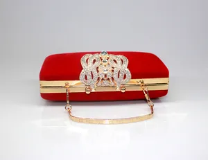 Detailed close-up of a red velvet evening clutch bag with a sparkling crown rhinestone clasp