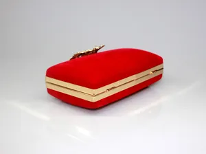 Detailed side view of an elegant red velvet clutch bag with a gold frame and crystal crown