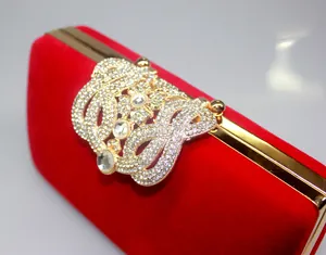 Macro view of crystal encrusted crown clasp on luxury red velvet bridal evening bag