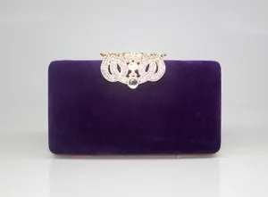 Detailed shot of a purple velvet evening clutch bag with crown rhinestone clasp