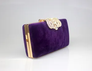 Detailed view of an elegant purple velvet evening clutch featuring a gold rhinestone crown clasp.