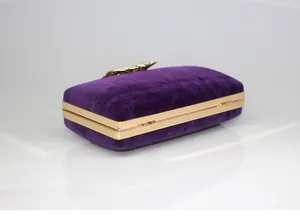 Side detail of purple velvet evening clutch with golden frame and rhinestone crown clasp