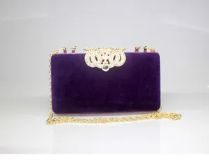 Elegant purple velvet evening clutch with a golden rhinestone crown clasp detail