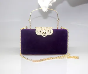 Detail of purple velvet evening clutch with elegant gold crown rhinestone buckle