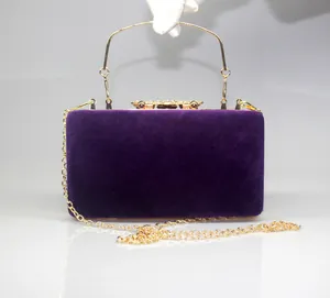 Detailed view of luxury purple velvet evening clutch featuring gold rhinestone crown clasp