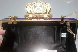Detailed interior view of purple velvet crown clutch bag with black lining and pocket