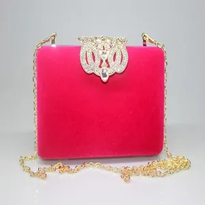 Detailed view of magenta velvet evening clutch bag with ornate crown rhinestone clasp