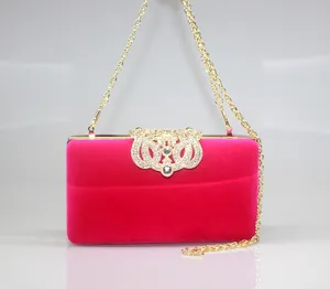 Close-up of fuchsia velvet evening clutch bag with sparkling rhinestone crown clasp