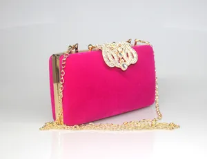 Detailed view of the sparkling rhinestone crown clasp on fuchsia velvet clutch bag.