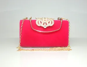 Close-up of luxury fuchsia velvet evening clutch with ornate crystal crown clasp