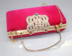Detail of pink velvet clutch bag with rhinestone crown clasp and gold chain strap