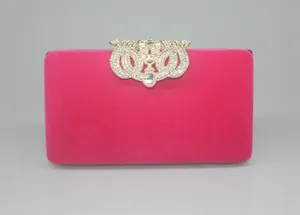 Close-up detail of a magenta velvet evening clutch bag with a crystal crown clasp
