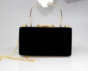 Detailed view of black velvet evening clutch bag with rhinestone crown clasp and gold handle