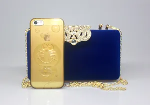 Detail view of the royal blue velvet crown clutch bag compared with a smartphone