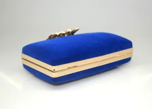 Detailed side view of blue velvet crown evening clutch bag with golden metal frame