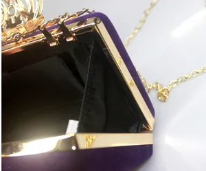 Close-up of internal lining and gold crown clasp on purple velvet evening bag