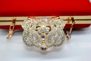 Detailed macro view of ornate rhinestone crown clasp on luxury red velvet evening clutch