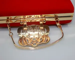 Close-up of decorative gold crown clasp on luxurious red velvet evening clutch bag