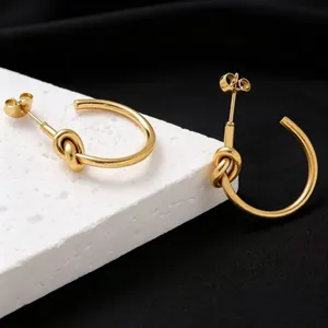 Detailed close-up of gold-plated titanium steel knot hoop earrings with polished finish