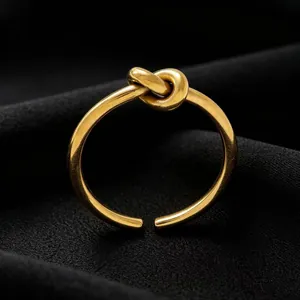 Close-up of elegant gold titanium steel love knot ring on black fabric background