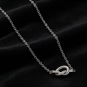 Close-up detail of silver stainless steel necklace featuring a minimalist knot pendant design