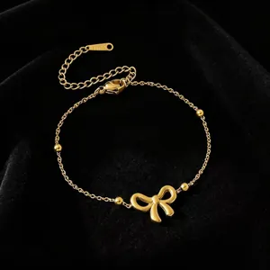 Detailweergave van een goudkleurige titaniumstalen armband met een zachte strik-hanger