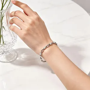 Gros plan détaillé d'un bracelet en acier argenté à maillons nez de porc sur un poignet