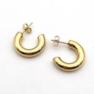 Detail of chunky gold-plated C-shaped stainless steel hoop earrings with high polish.